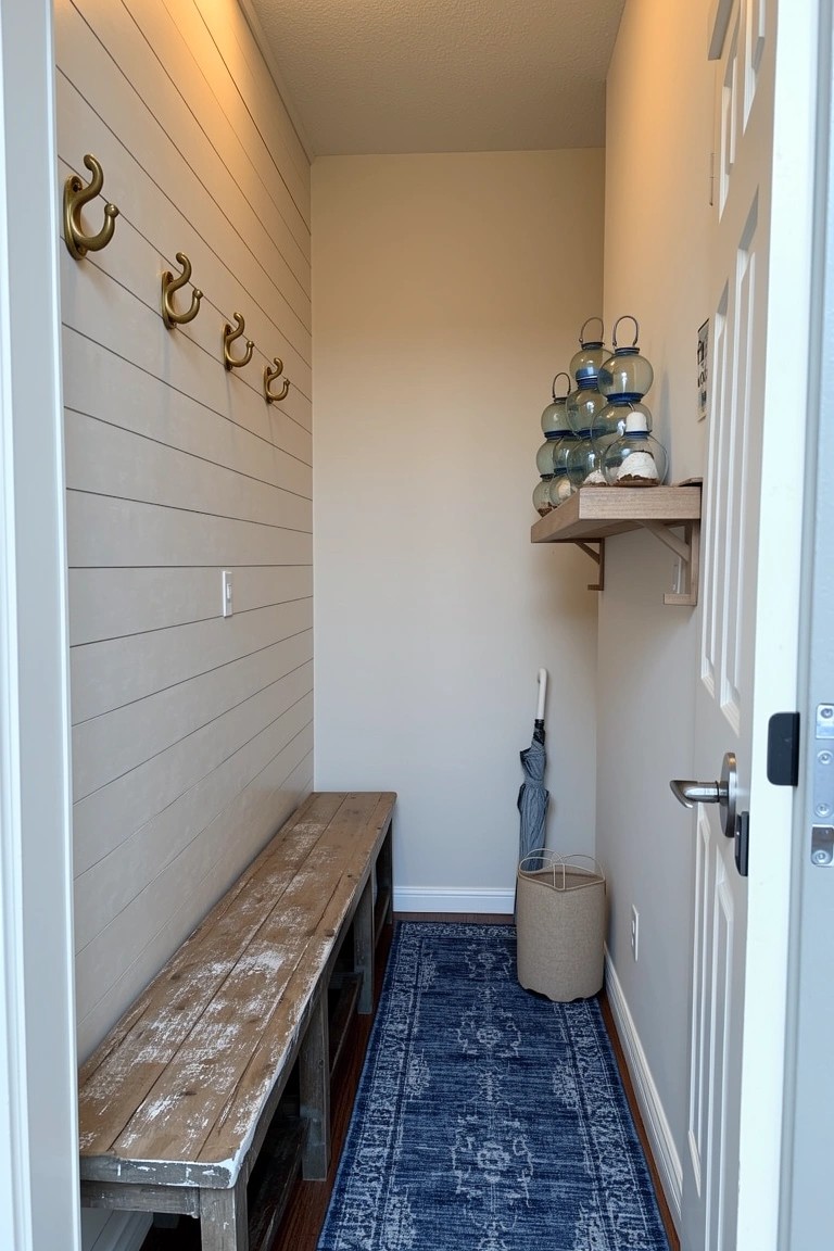 Cozy coastal mudroom with shiplap walls, wooden bench, brass hooks, blue glass decor on shelf, and woven basket