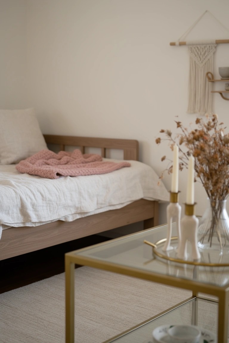 Cozy modern boho daybed nook with pink knit blanket on neutral sheets, dried pampas grass in vase, and gold tray table