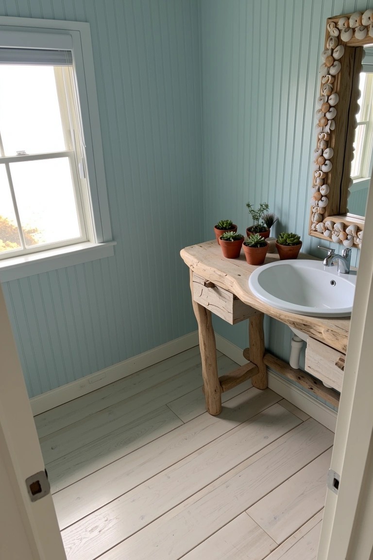 Cozy small bathroom with curved rustic wooden vanity, white round sink, potted plants, shell mirror, light blue paneled walls, and whitewashed wood floors