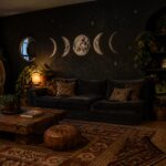 A living room with a dark accent wall painted with moon phase illustrations above a dark sofa and wooden coffee table.