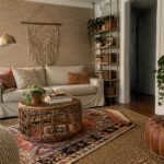 Cozy bohemian living room with white sofa, rattan table, leather poufs, and macrame.