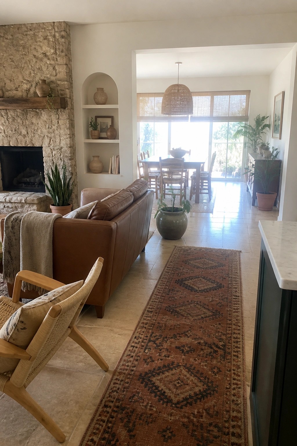 Brown leather sofa, woven chair, and patterned runner rug in open living room with fireplace